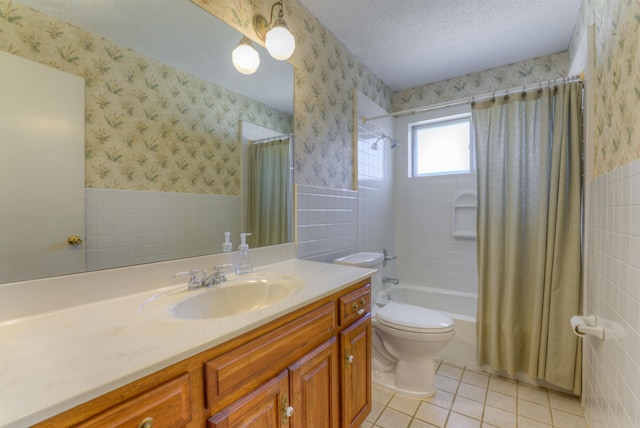 bathroom featuring a wainscoted wall, a textured ceiling, and wallpapered walls