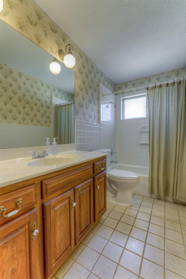 bathroom with wallpapered walls, a textured ceiling, and a wainscoted wall