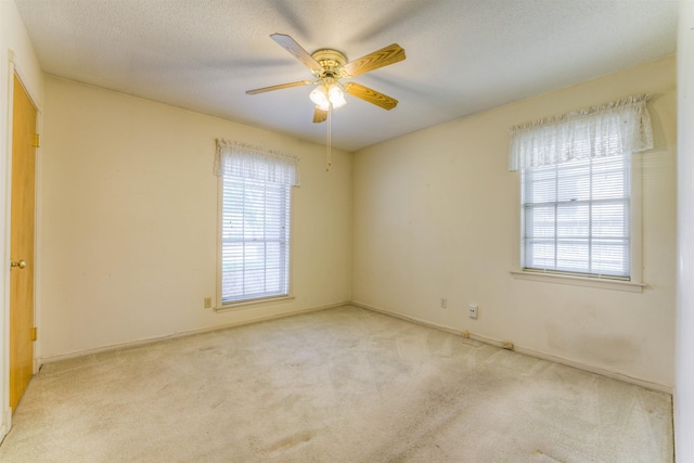 unfurnished room with a textured ceiling, carpet floors, a ceiling fan, and baseboards