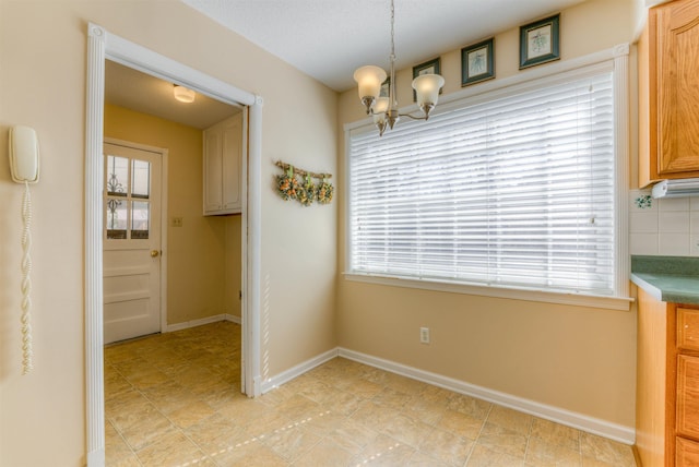 unfurnished dining area with an inviting chandelier, a wealth of natural light, and baseboards