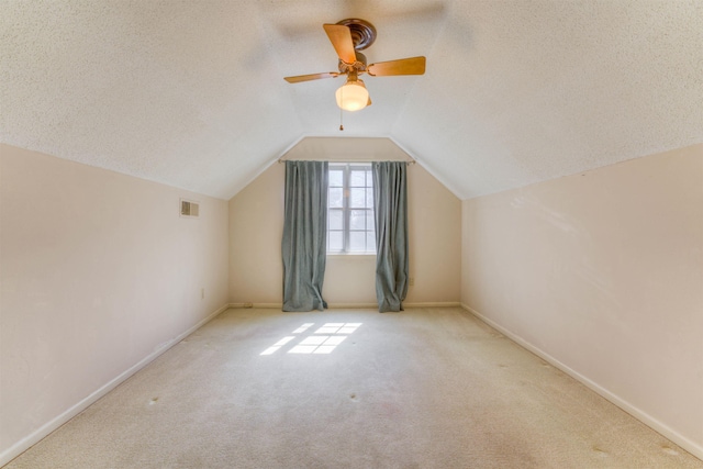 additional living space featuring baseboards, visible vents, lofted ceiling, carpet, and a textured ceiling