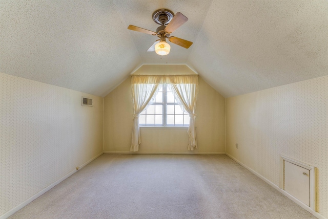 bonus room featuring wallpapered walls, visible vents, lofted ceiling, carpet, and a textured ceiling