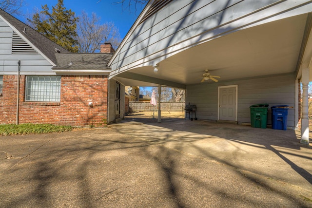 exterior space featuring brick siding, a chimney, a shingled roof, ceiling fan, and driveway