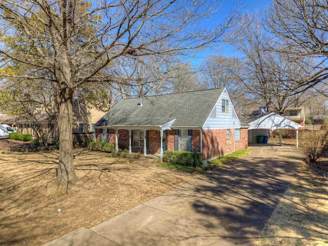 view of front facade featuring a carport, concrete driveway, brick siding, and roof with shingles