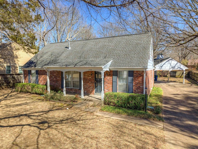 view of front of house with brick siding, a porch, a shingled roof, and fence