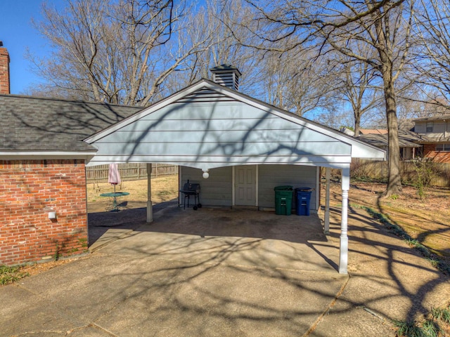 view of outbuilding featuring driveway, fence, and a carport