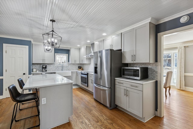 kitchen featuring light countertops, appliances with stainless steel finishes, gray cabinets, and wall chimney range hood