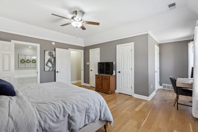 bedroom featuring light wood finished floors, visible vents, ensuite bathroom, ornamental molding, and baseboards