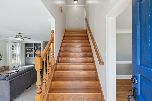 stairway with built in shelves, wood finished floors, a ceiling fan, and baseboards