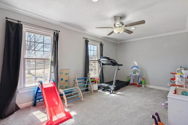 exercise area with a textured ceiling, ornamental molding, carpet, and baseboards