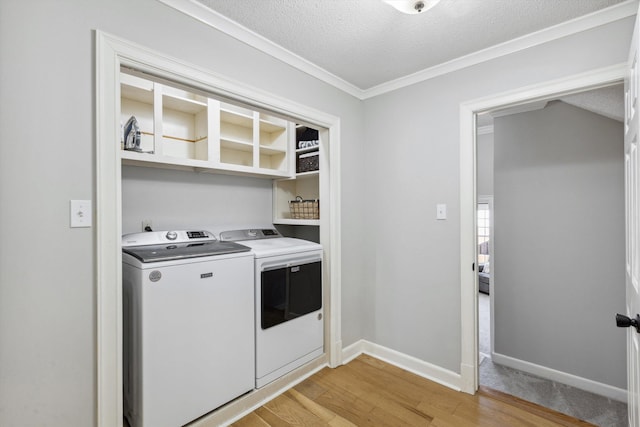 clothes washing area featuring a textured ceiling, laundry area, baseboards, light wood-style floors, and washer and clothes dryer