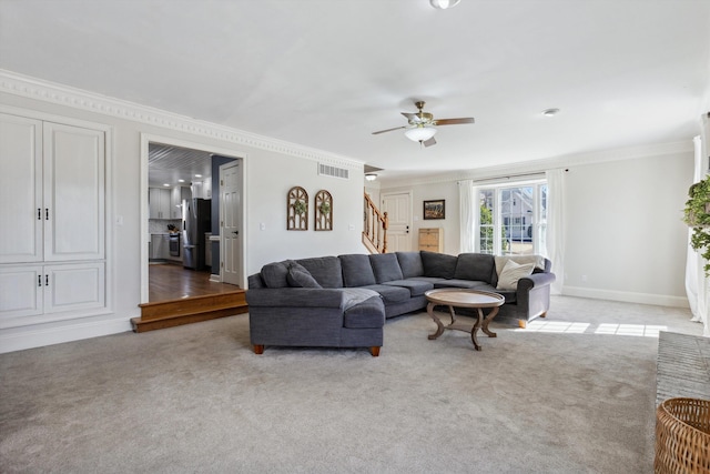 carpeted living room featuring crown molding, visible vents, stairway, ceiling fan, and baseboards