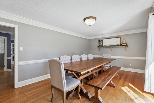 dining area with ornamental molding, wood finished floors, and baseboards