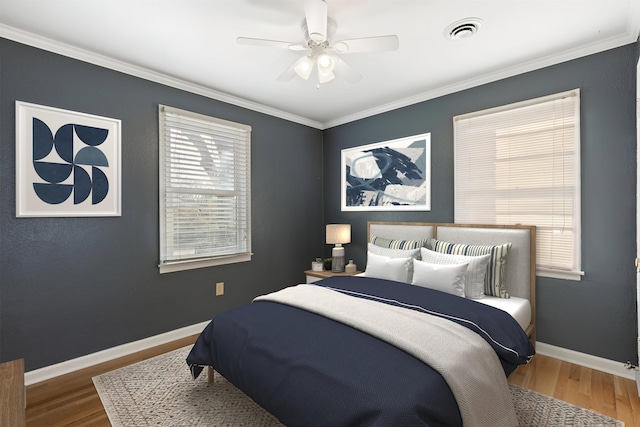 bedroom featuring visible vents, crown molding, baseboards, and wood finished floors