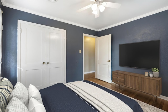 bedroom featuring a closet, ornamental molding, a ceiling fan, wood finished floors, and baseboards