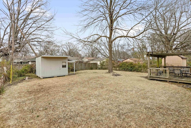 view of yard featuring an outbuilding, a storage shed, fence, and a deck