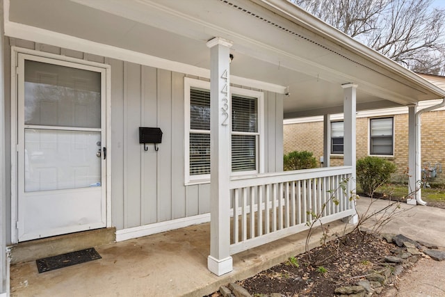 entrance to property with a porch and brick siding