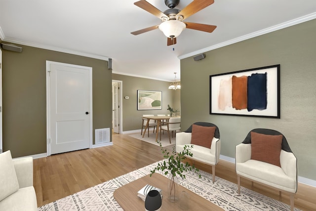 living area featuring ornamental molding, light wood-type flooring, visible vents, and baseboards