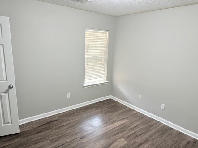 unfurnished room featuring a textured ceiling, dark wood-style flooring, and baseboards