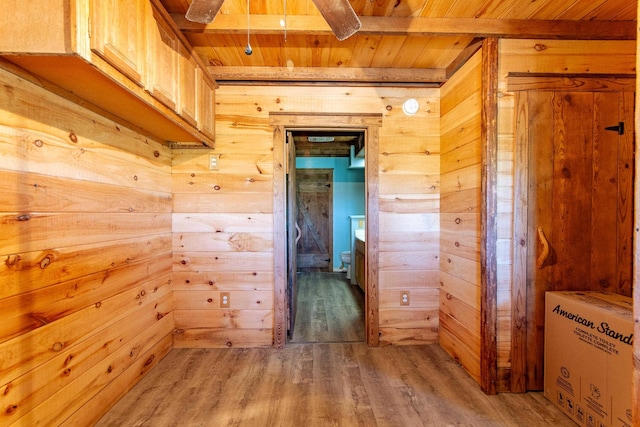 corridor with wooden ceiling, wood walls, beam ceiling, and light wood-style floors