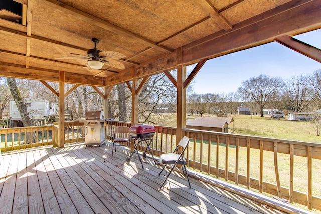 deck featuring a ceiling fan, a lawn, and area for grilling