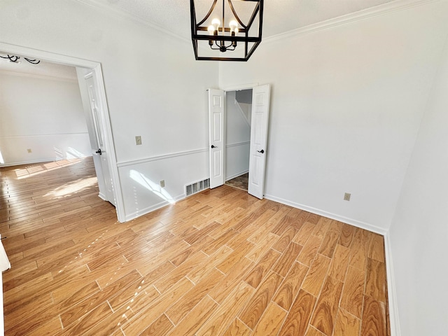 unfurnished dining area featuring light wood finished floors, baseboards, visible vents, and ornamental molding