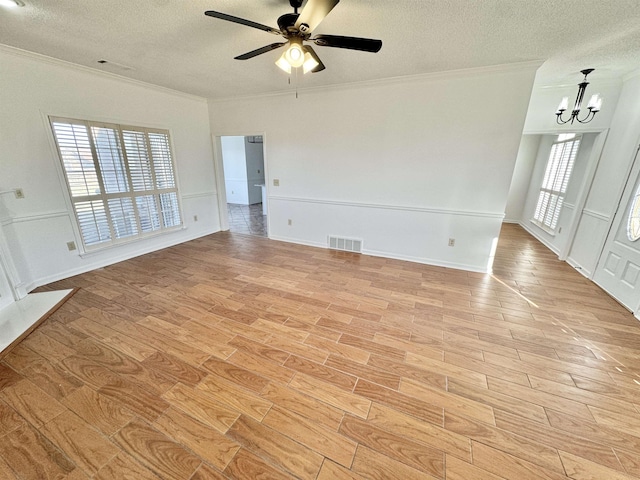 unfurnished room with ornamental molding, light wood-style flooring, a textured ceiling, and visible vents