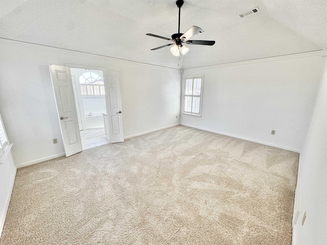 empty room with a textured ceiling, ceiling fan, carpet floors, visible vents, and baseboards