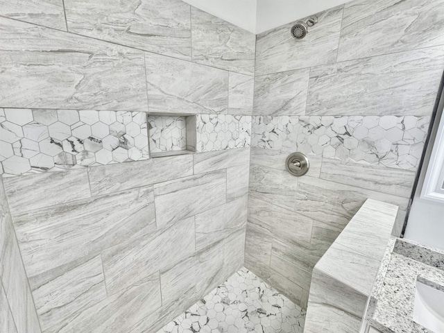 full bathroom featuring a tile shower and a sink