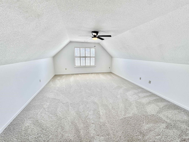 bonus room with baseboards, lofted ceiling, ceiling fan, a textured ceiling, and carpet flooring