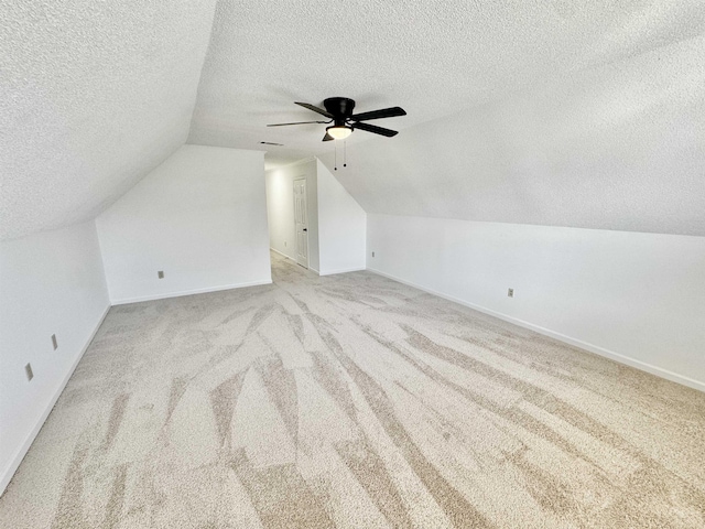 additional living space with carpet floors, vaulted ceiling, a textured ceiling, and baseboards