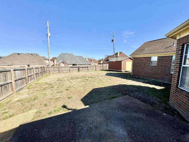 view of yard featuring an outbuilding, a fenced backyard, and a shed