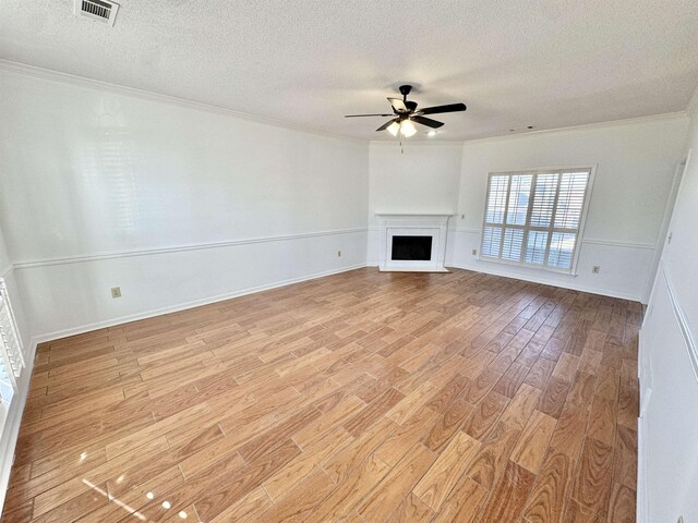 unfurnished living room featuring crown molding, light wood-type flooring, visible vents, and a fireplace