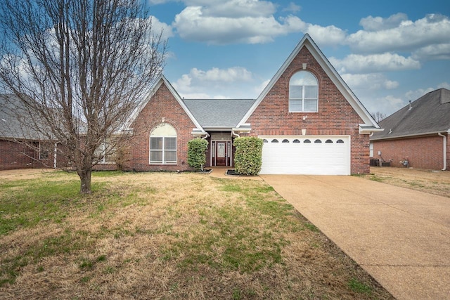 traditional-style home featuring driveway, brick siding, a front yard, and a shingled roof