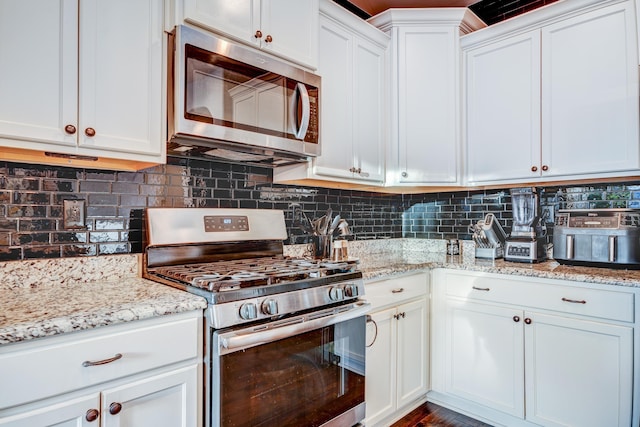 kitchen featuring appliances with stainless steel finishes, backsplash, white cabinetry, and light stone countertops