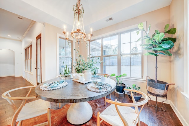 dining space with baseboards, arched walkways, and wood finished floors