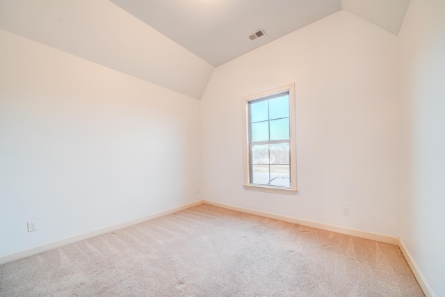 empty room with carpet floors, baseboards, visible vents, and vaulted ceiling