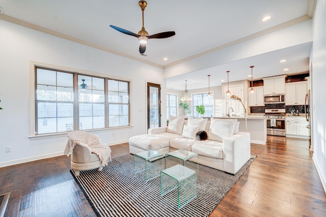 living area featuring dark wood finished floors, recessed lighting, ornamental molding, baseboards, and ceiling fan with notable chandelier