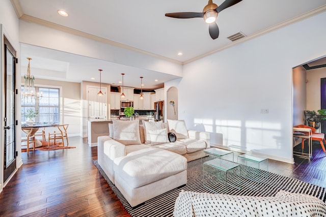 living area featuring baseboards, visible vents, arched walkways, dark wood-style flooring, and ceiling fan with notable chandelier