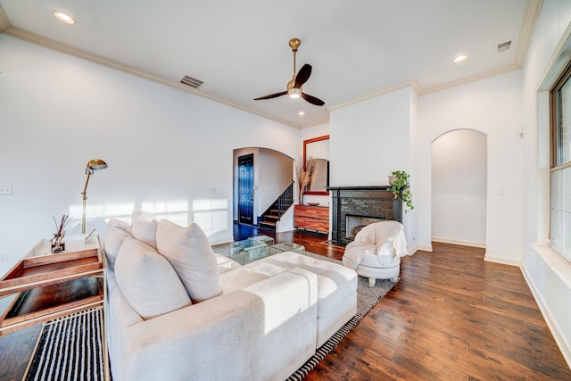 living area with arched walkways, a stone fireplace, wood-type flooring, and visible vents