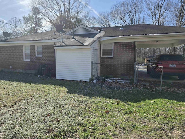 rear view of house with a yard, brick siding, and a carport