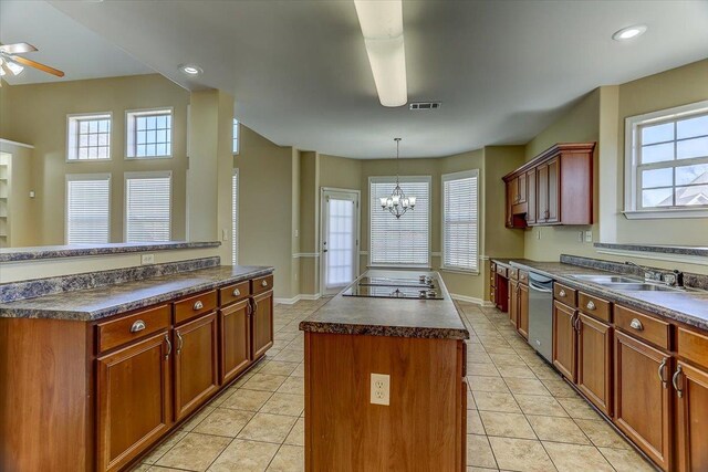 kitchen with visible vents, dark countertops, stovetop with downdraft, a center island, and ceiling fan with notable chandelier