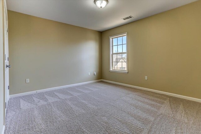 carpeted spare room with visible vents and baseboards