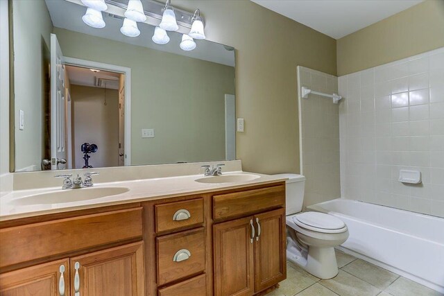 bathroom featuring tile patterned flooring, a sink, toilet, and double vanity