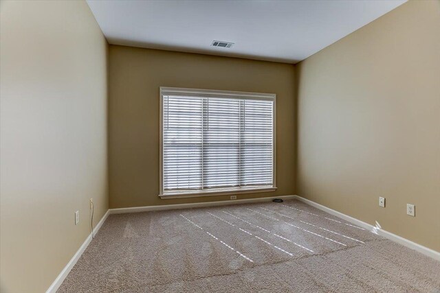 empty room with carpet flooring, visible vents, and baseboards