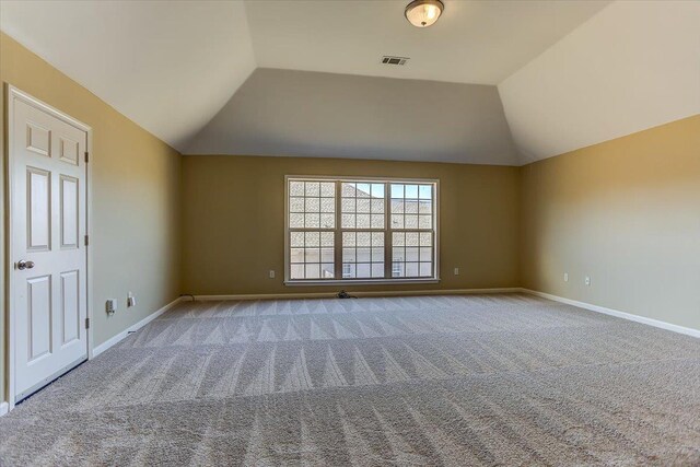 carpeted spare room with lofted ceiling, baseboards, and visible vents