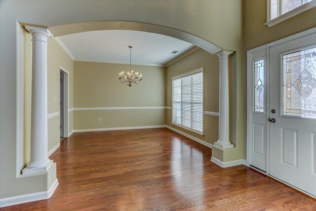 entrance foyer with arched walkways, ornamental molding, wood finished floors, and ornate columns