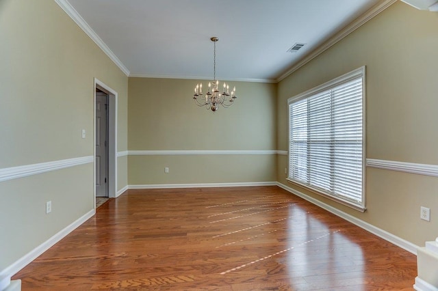 empty room featuring visible vents, wood finished floors, and ornamental molding