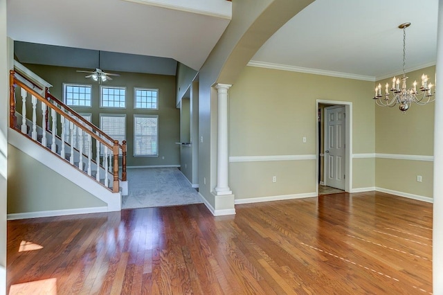 foyer with arched walkways, decorative columns, wood finished floors, baseboards, and ceiling fan with notable chandelier