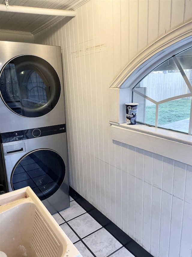 laundry room featuring tile patterned floors, stacked washer and clothes dryer, and laundry area